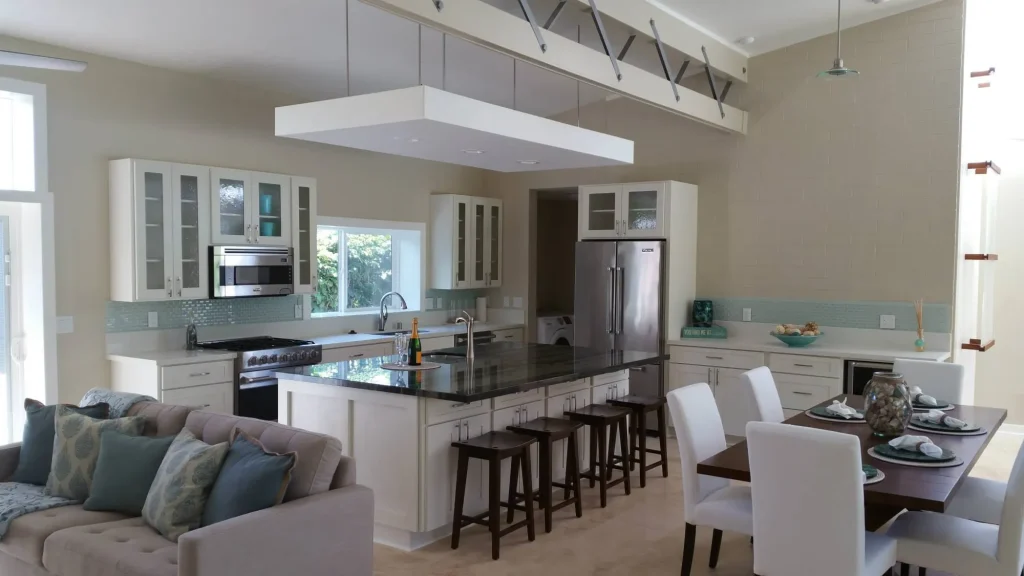 Open kitchen, dining and living area with white cabinetry, dark counters and a seating island